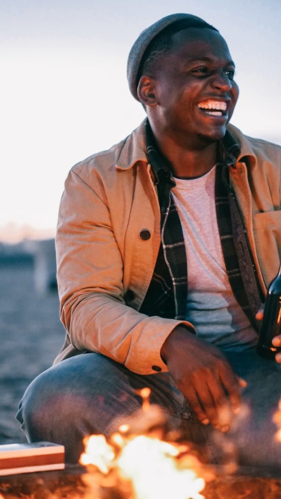 man laughing around a fire
